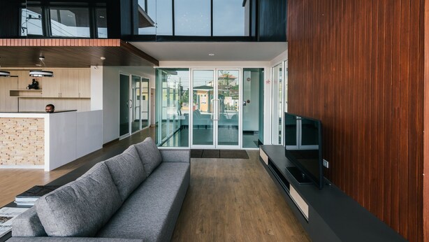 A modern interior with a sofa, wooden flooring, and a TV on a black stand. - MT Park Residence (Chonburi)