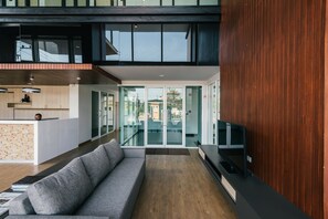 A modern interior with a sofa, wooden flooring, and a TV on a black stand. - MT Park Residence (Chonburi)