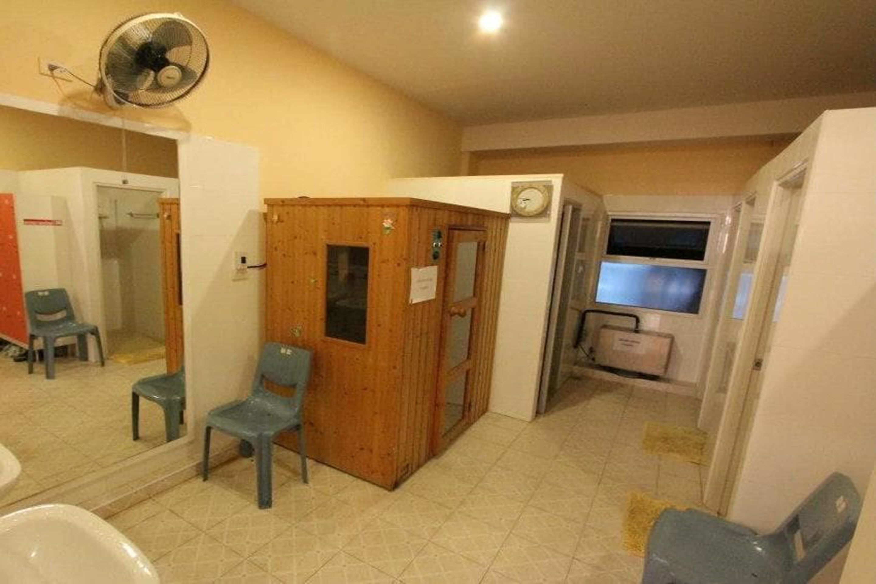 A room with a wooden partition, a fan, a clock, and a television.