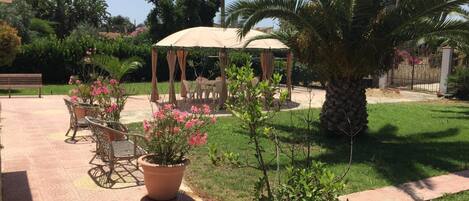 Un patio con pérgola, mobiliario exterior y plantas en macetas.