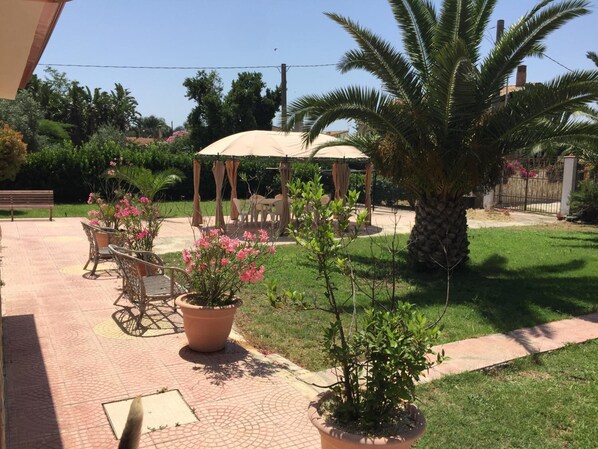 A patio area with a pergola, outdoor seating, and potted plants. - Rudy Arenaile (Syracuse)
