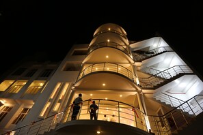 Un edificio de varios pisos con un diseño arquitectónico moderno, que destaca una estructura cilíndrica central y varios balcones.