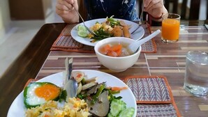Una persona sentada a una mesa con diversos platos, incluyendo arroz, verduras y un tazón de sopa.