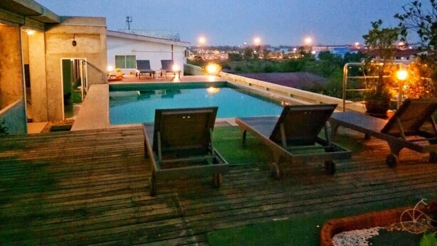 Una piscina con sillones de descanso y una terraza de madera.