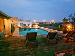 A swimming pool with lounge chairs and a wooden deck.
