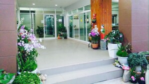 Una entrada moderna con puertas de vidrio, un pilar de madera y varias plantas en macetas.