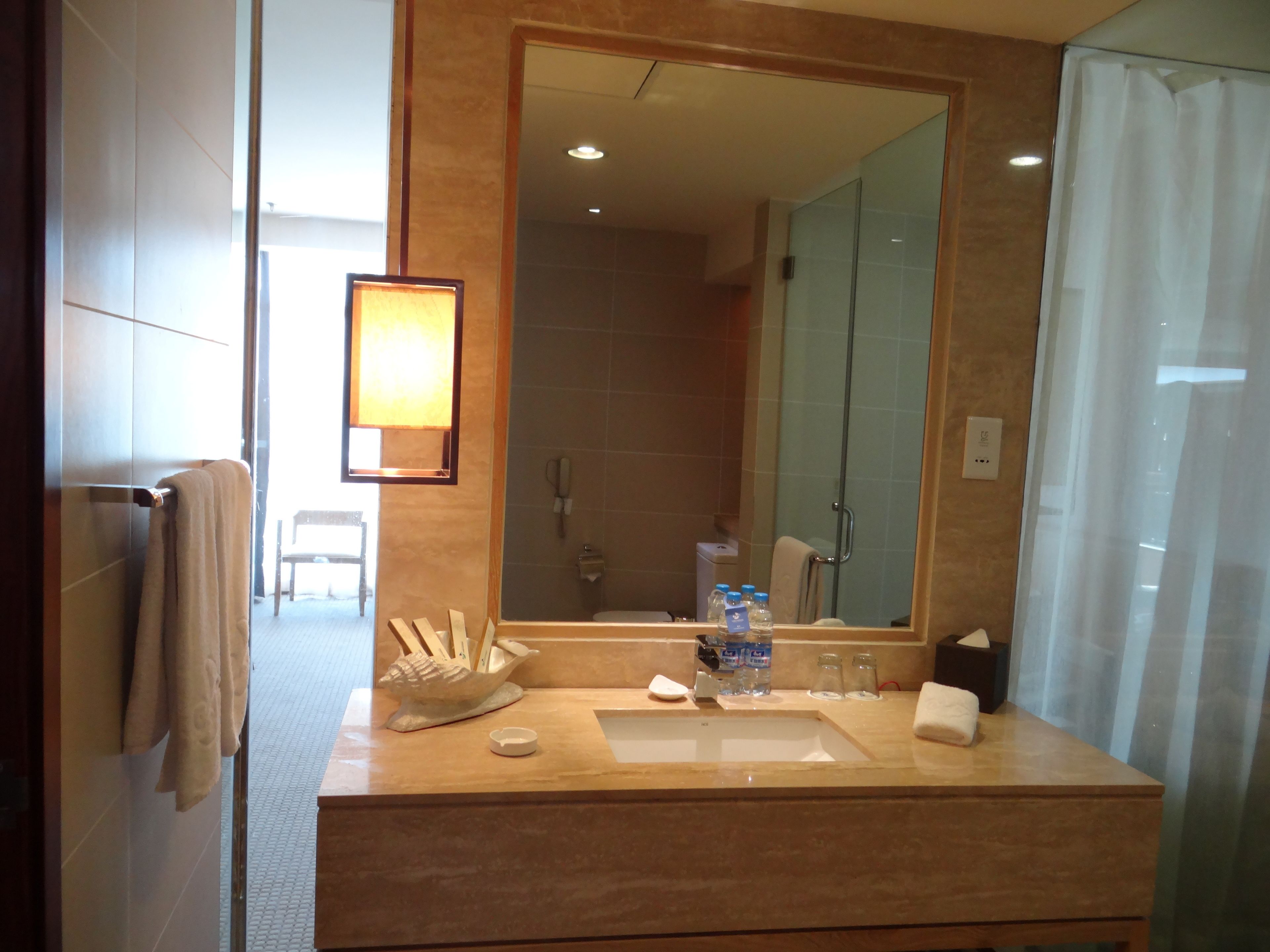 A modern bathroom with a large mirror, a sink, and a shower.