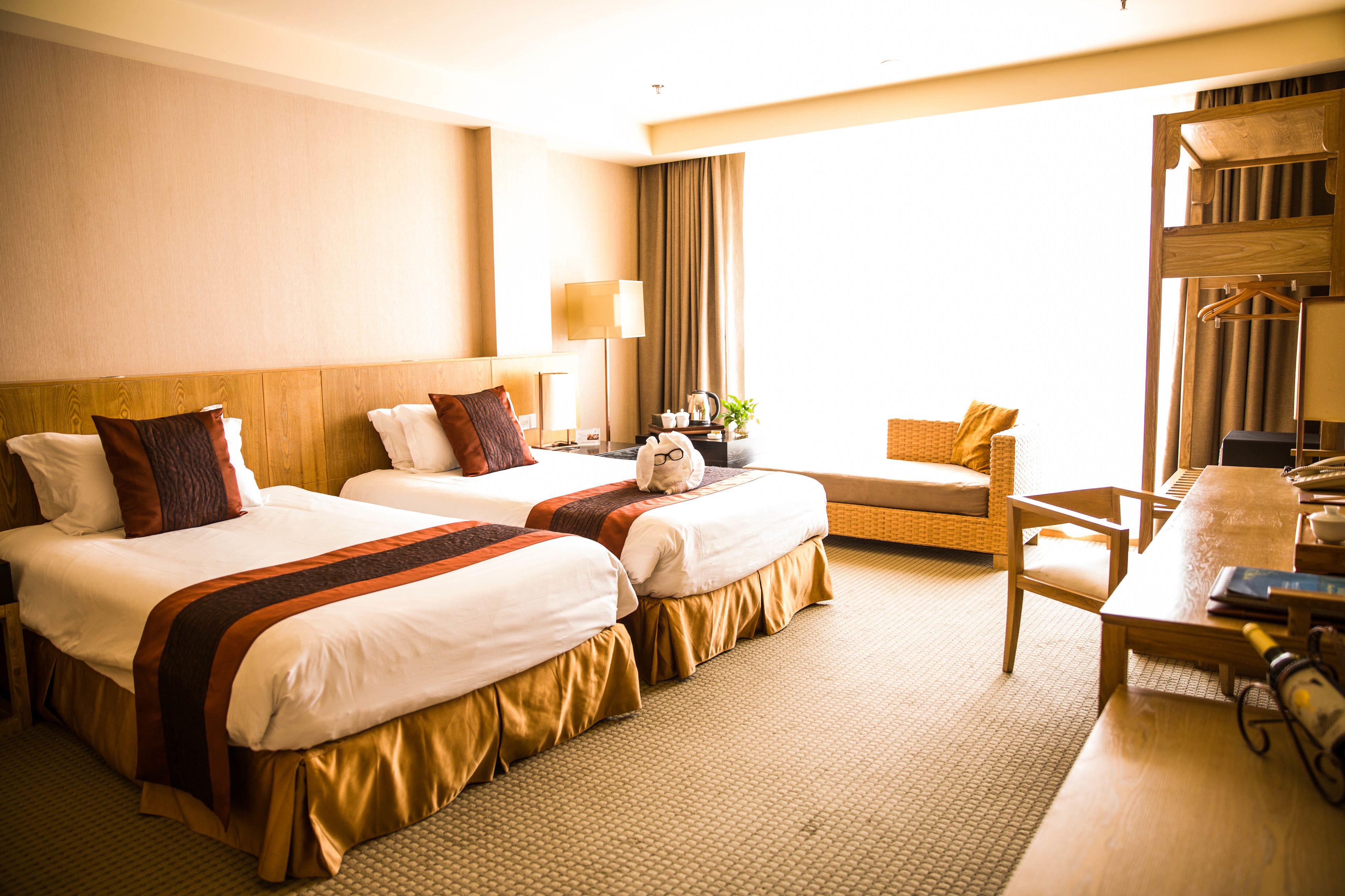 Quarto de hotel com duas camas, um sofá, uma mesa e uma cadeira.