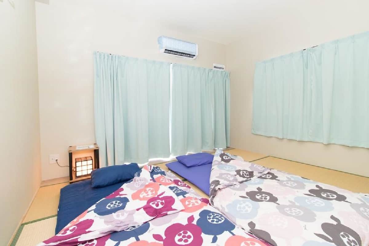 A room with two beds, a heater, and light curtains.