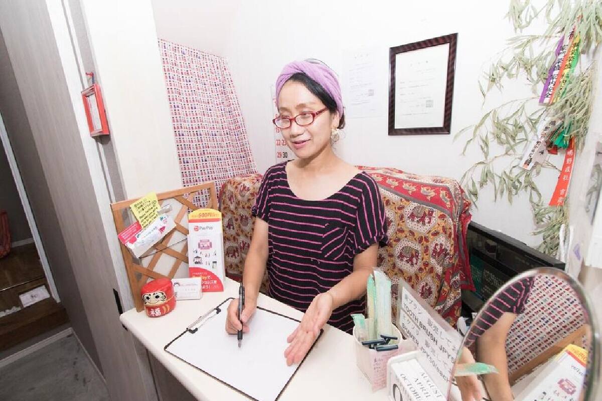 A person at a desk with a clipboard, a mirror, and various items on the desk.