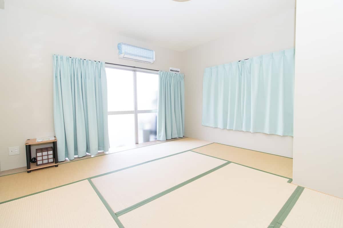 A room with tatami flooring, a sliding door, and light blue curtains.