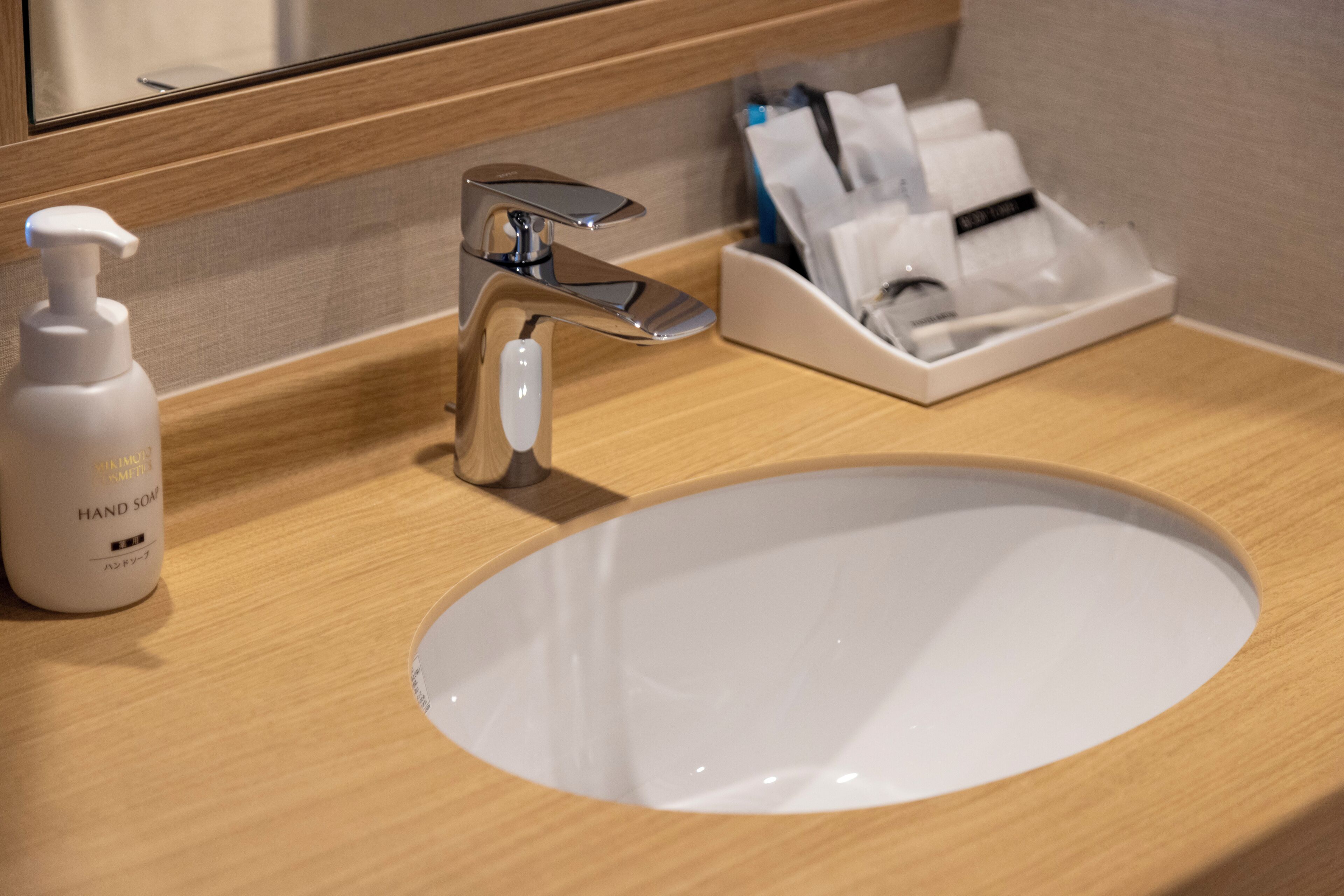 A bathroom sink with a chrome faucet, a bottle of hand soap, and a tissue dispenser.