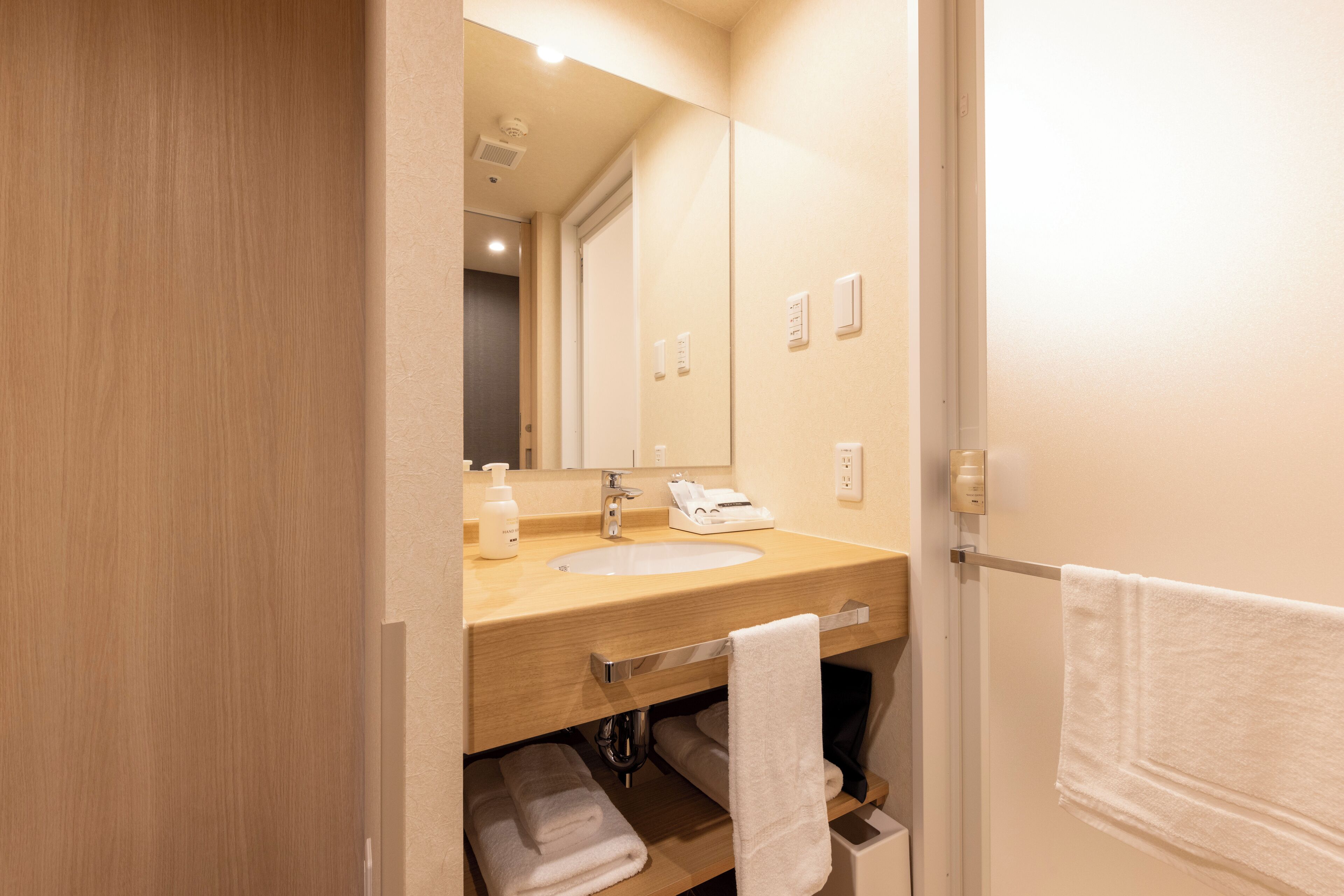 A bathroom with a wooden vanity, a sink, a mirror, and a towel rack.