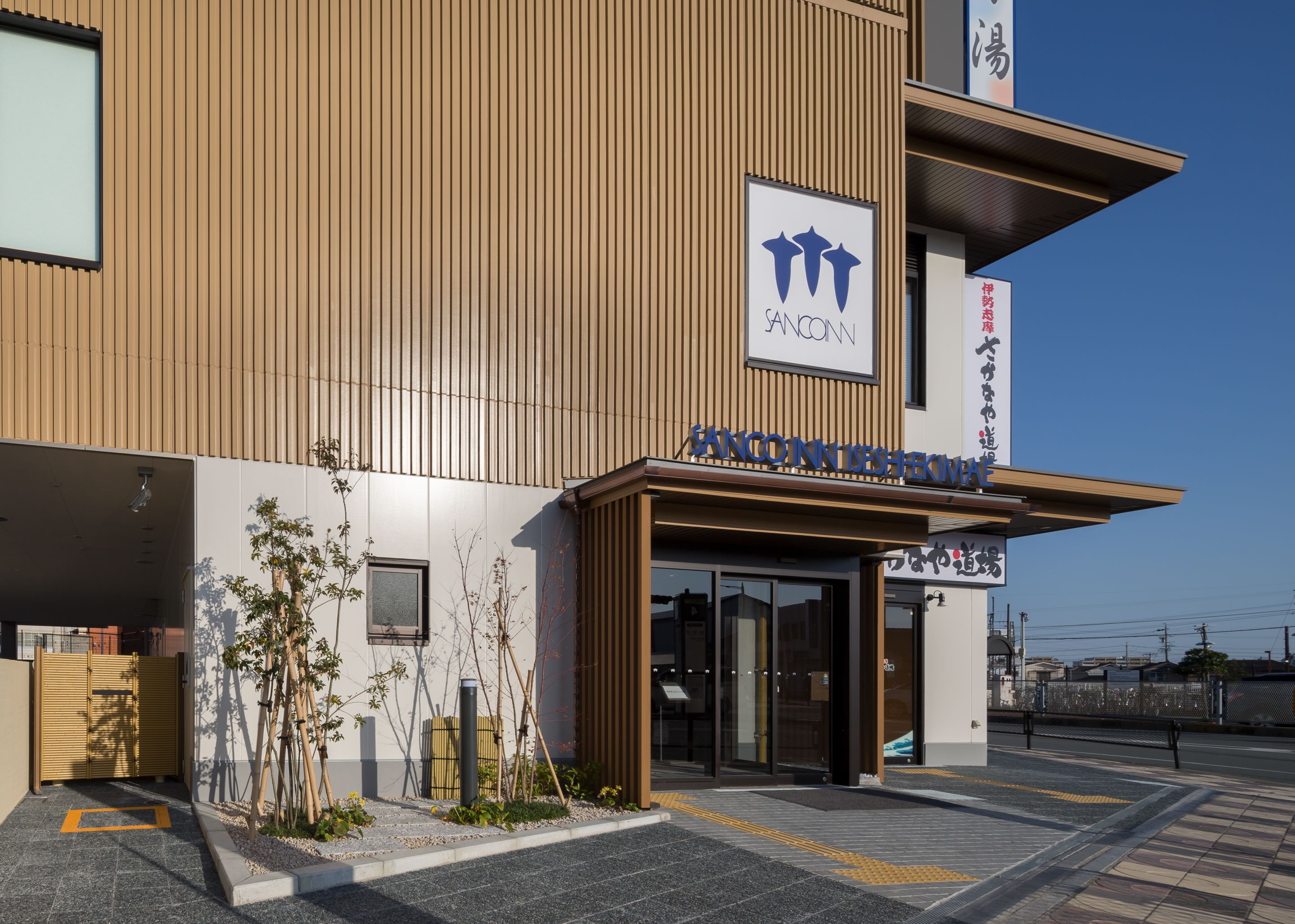A modern building with a wooden facade, a sign reading "SANCONN," and a clear sky.