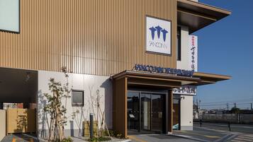 A modern building with a wooden facade, a sign reading "SANCONN," and a clear sky.