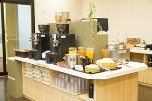 Un buffet de petit-déjeuner proposant une variété d’aliments et de boissons, notamment des céréales, des machines à café et des distributeurs de jus.