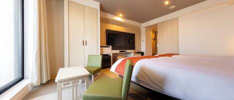 Habitación de hotel con cama, escritorio, silla y televisión.