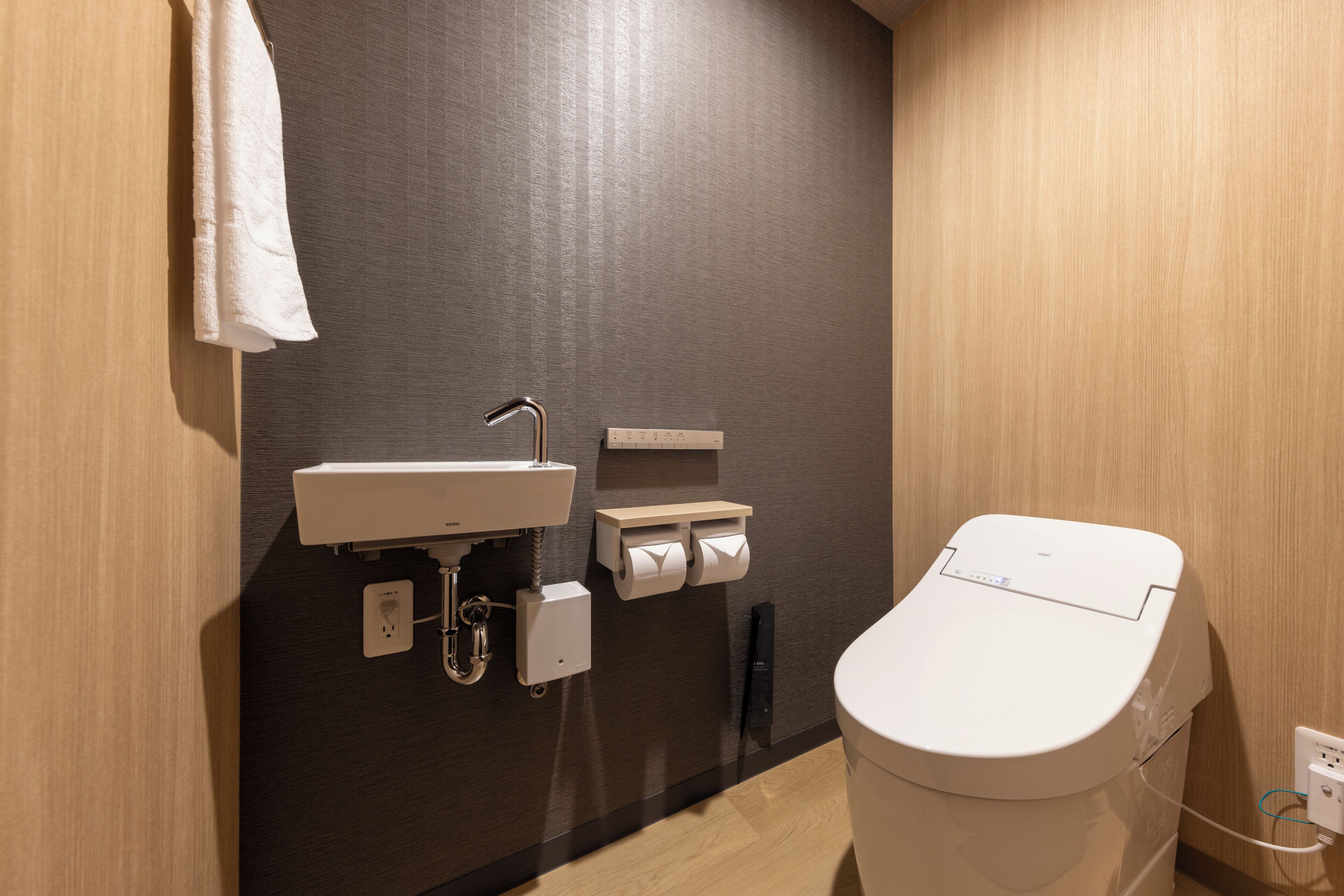 A modern bathroom with a toilet, sink, and towel rack.