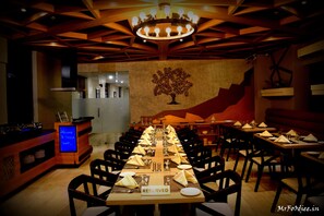 A restaurant with a long table set for a meal, a 'RESERVED' sign, and a wall mural of a tree. - The Centrepoint (Chennai)