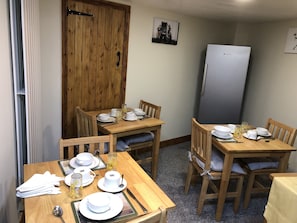 Un espace repas avec des tables et des chaises en bois, agrémenté de vaisselle et de verrerie blanche.