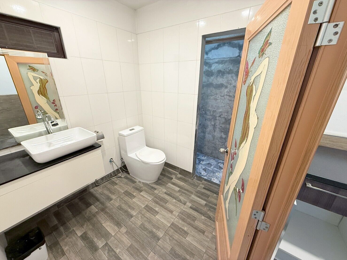 Un baño moderno con lavamanos, inodoro y zona de ducha blancos.