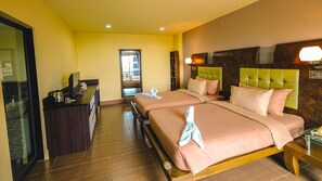 A hotel room with two beds, a desk with a computer, and a view of the outside through a window. - SPM Residence (Si Racha)