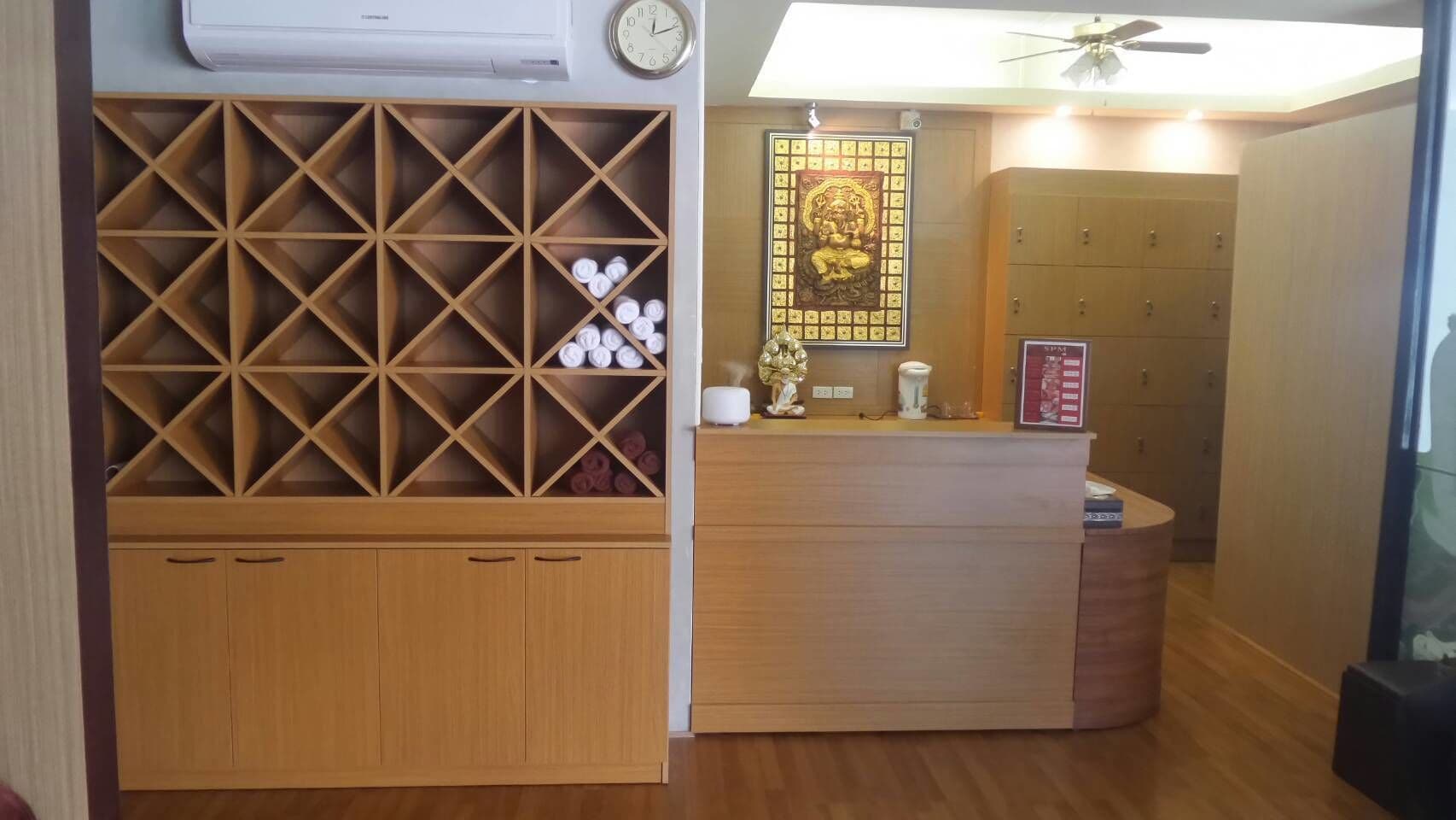 A reception area with a wooden desk, a clock, and a decorative wall piece.