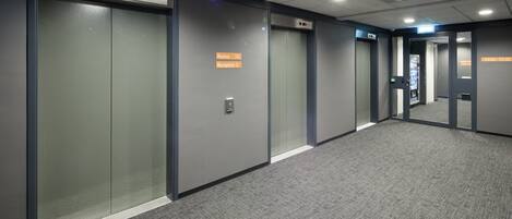 A hallway with elevators and a vending machine.