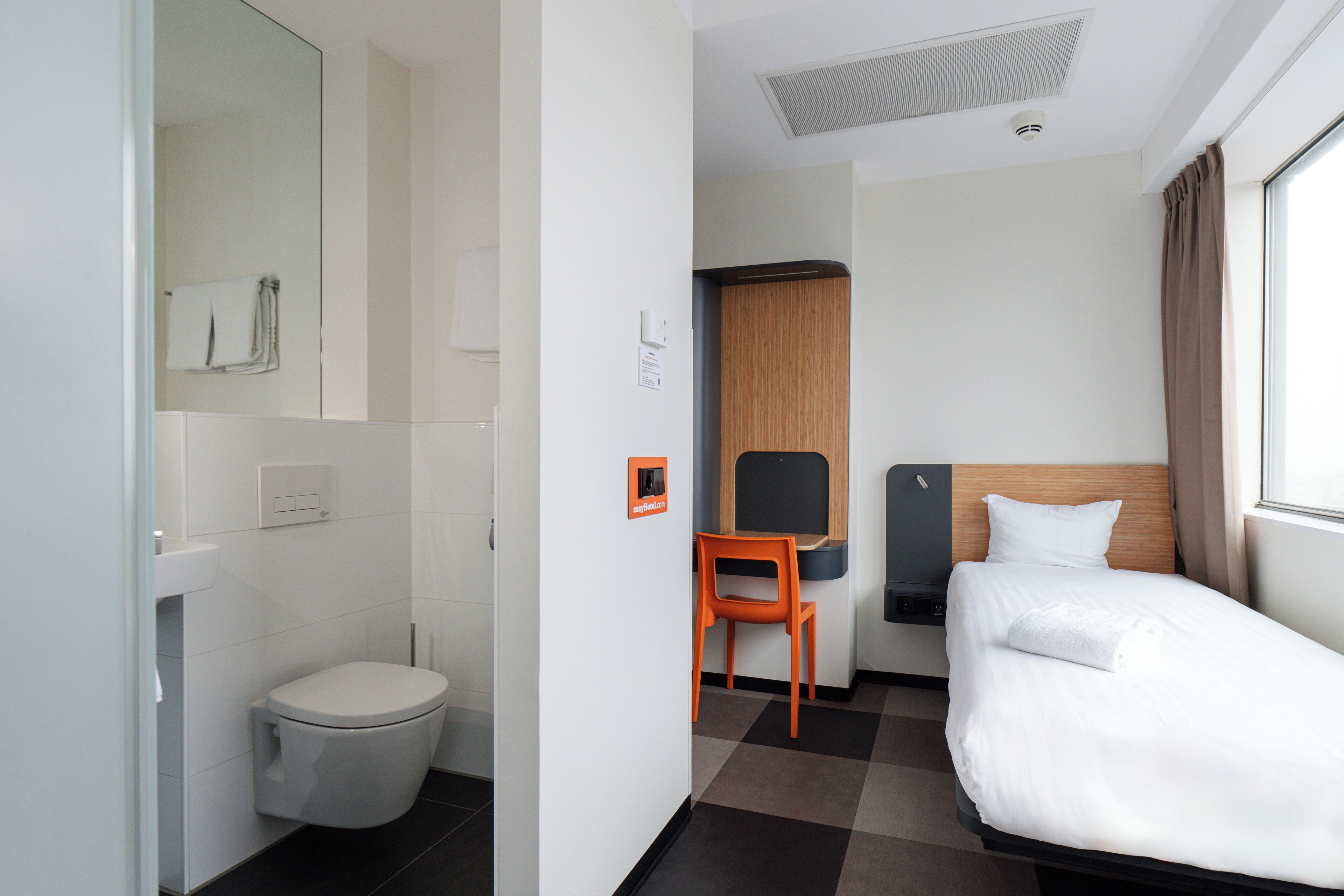 Une chambre d’hôtel équipée de toilettes, d’un lit, d’une chaise et d’un bureau.
