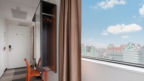 A hotel room with a view of a cityscape, a desk with a chair, and a wardrobe. - easyHotel Amsterdam Zaandam (Zaandam)