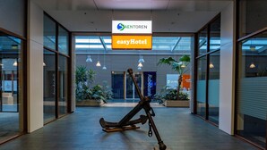A modern lobby with a large anchor sculpture, glass walls, and signs for 'Saentorén' and 'easyHotel'. - easyHotel Amsterdam Zaandam (Zaandam)