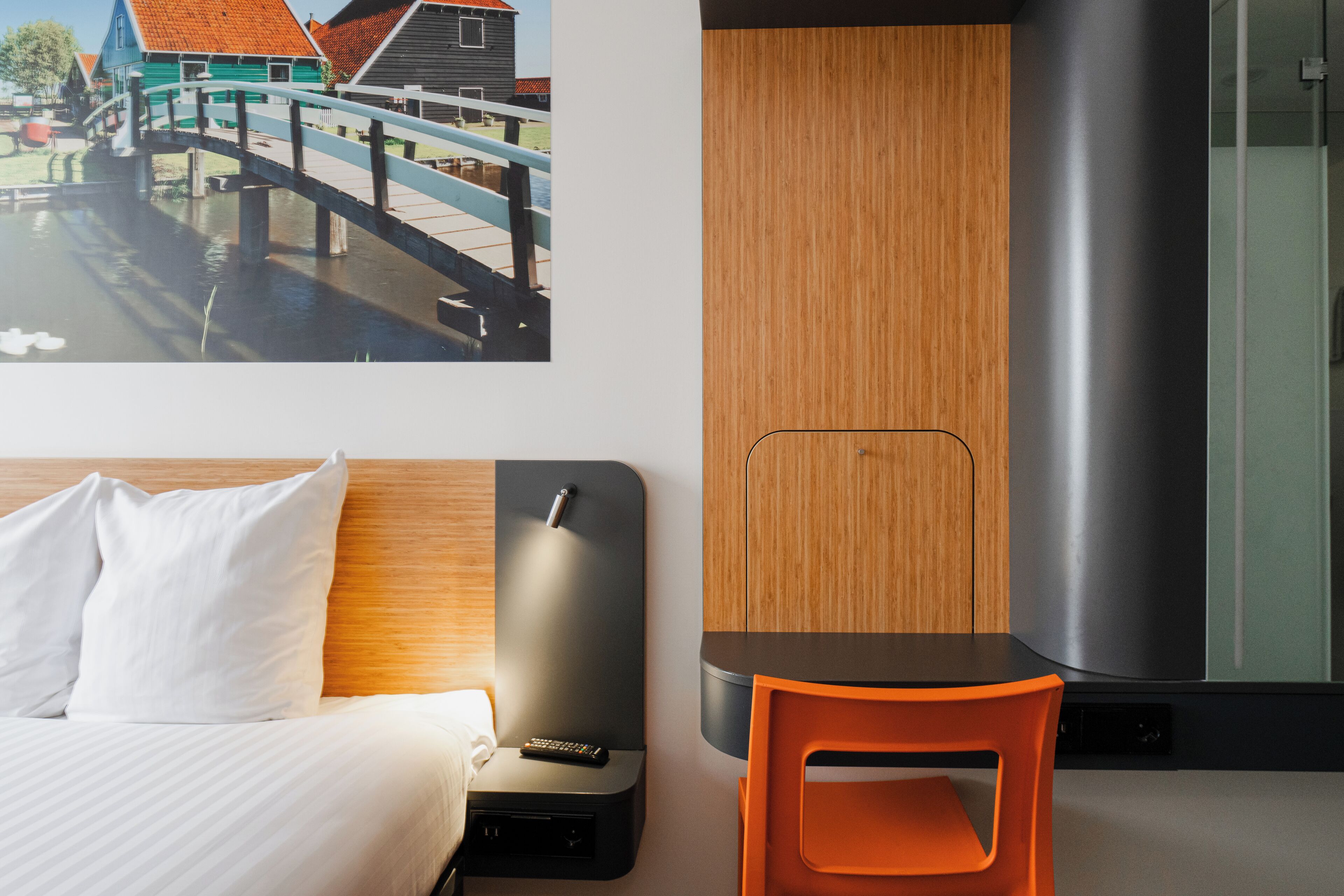 Una habitación de hotel con una cama, una mesita, una silla, un televisor y un armario de madera.