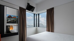 A hotel room with a large bed, a window with curtains, a flat-screen TV mounted on the wall, and a nightstand with a lamp. - easyHotel Amsterdam Zaandam (Zaandam)