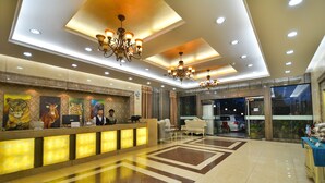 A hotel lobby with a reception desk, chandeliers, and a tiled floor. - Arirang Hotel (Kampala)