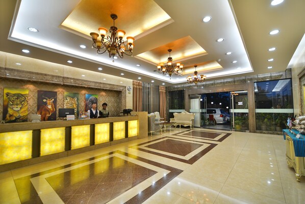 A hotel lobby with a reception desk, chandeliers, and a tiled floor. - Arirang Hotel (Kampala)