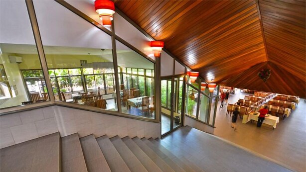 A modern interior with a staircase leading to a dining area with natural light and wooden ceiling. - Arirang Hotel (Kampala)