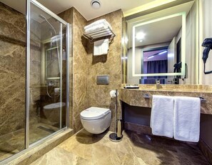 A modern bathroom with a glass-enclosed shower, a toilet, and a vanity with a mirror. - Hann Hotel (Istanbul)