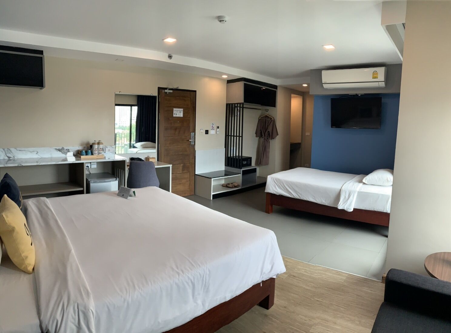 A hotel room with a large bed, a desk, a chair, a TV, and a wardrobe.