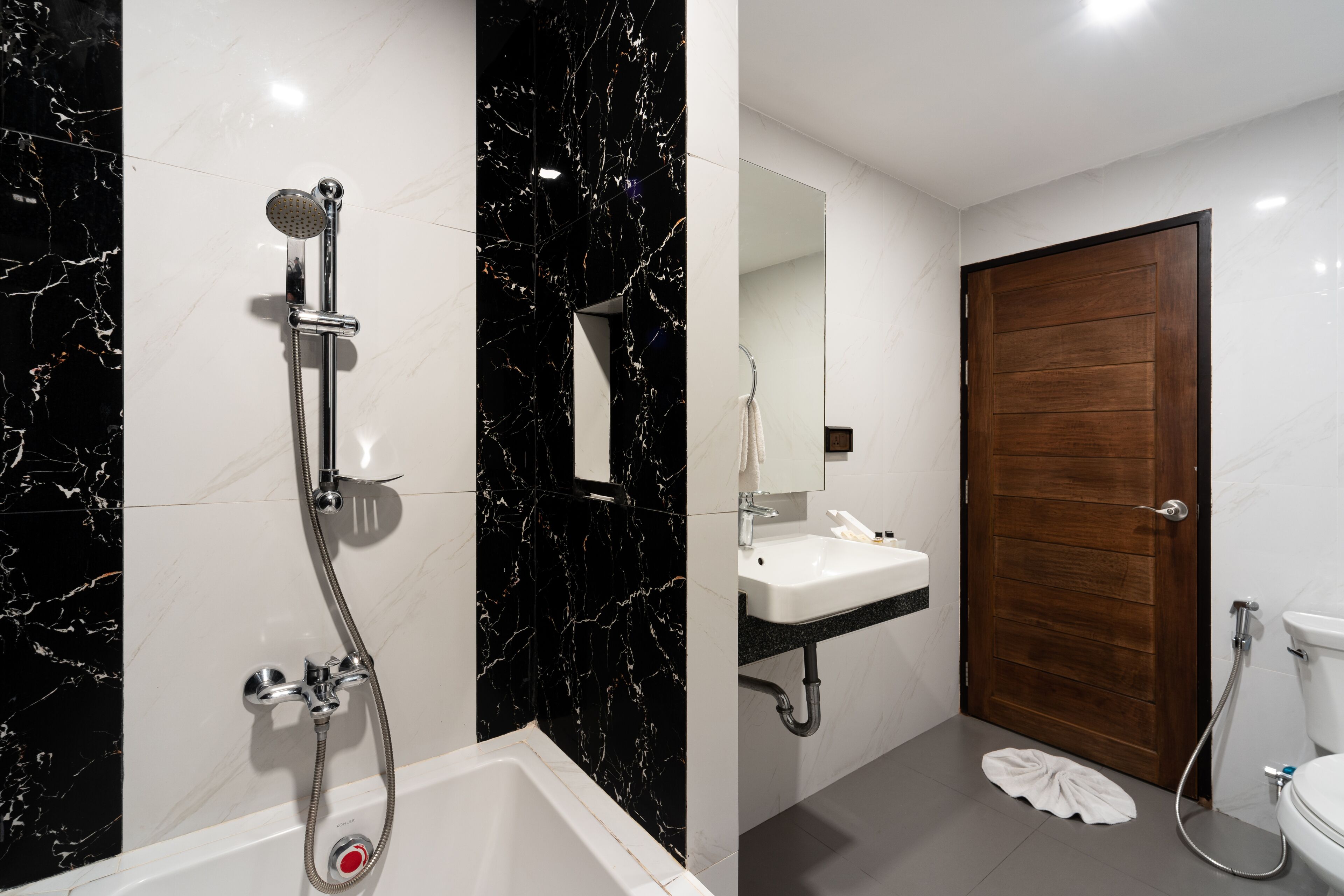 A modern bathroom with a bathtub, a shower, a sink, and a toilet.
