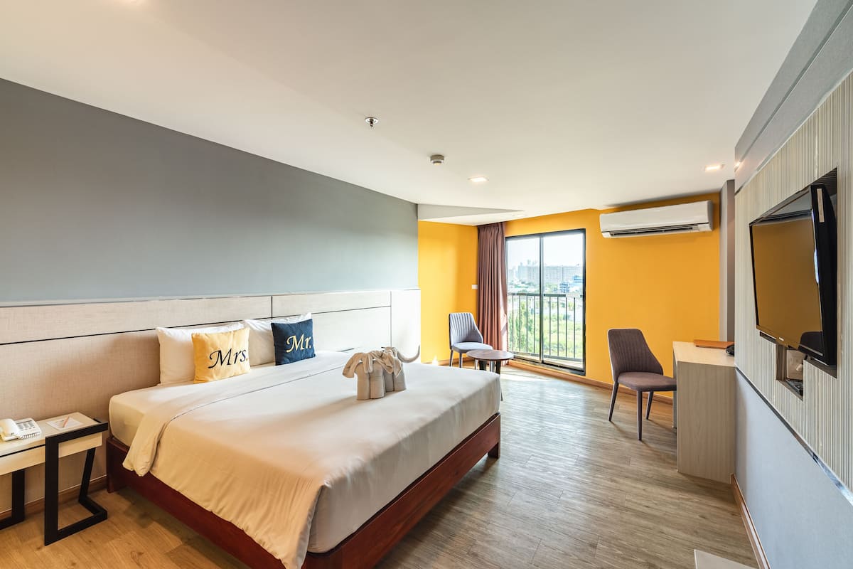 Ein Hotelzimmer mit Bett, Nachttisch, Stuhl, Schreibtisch und Fernseher.