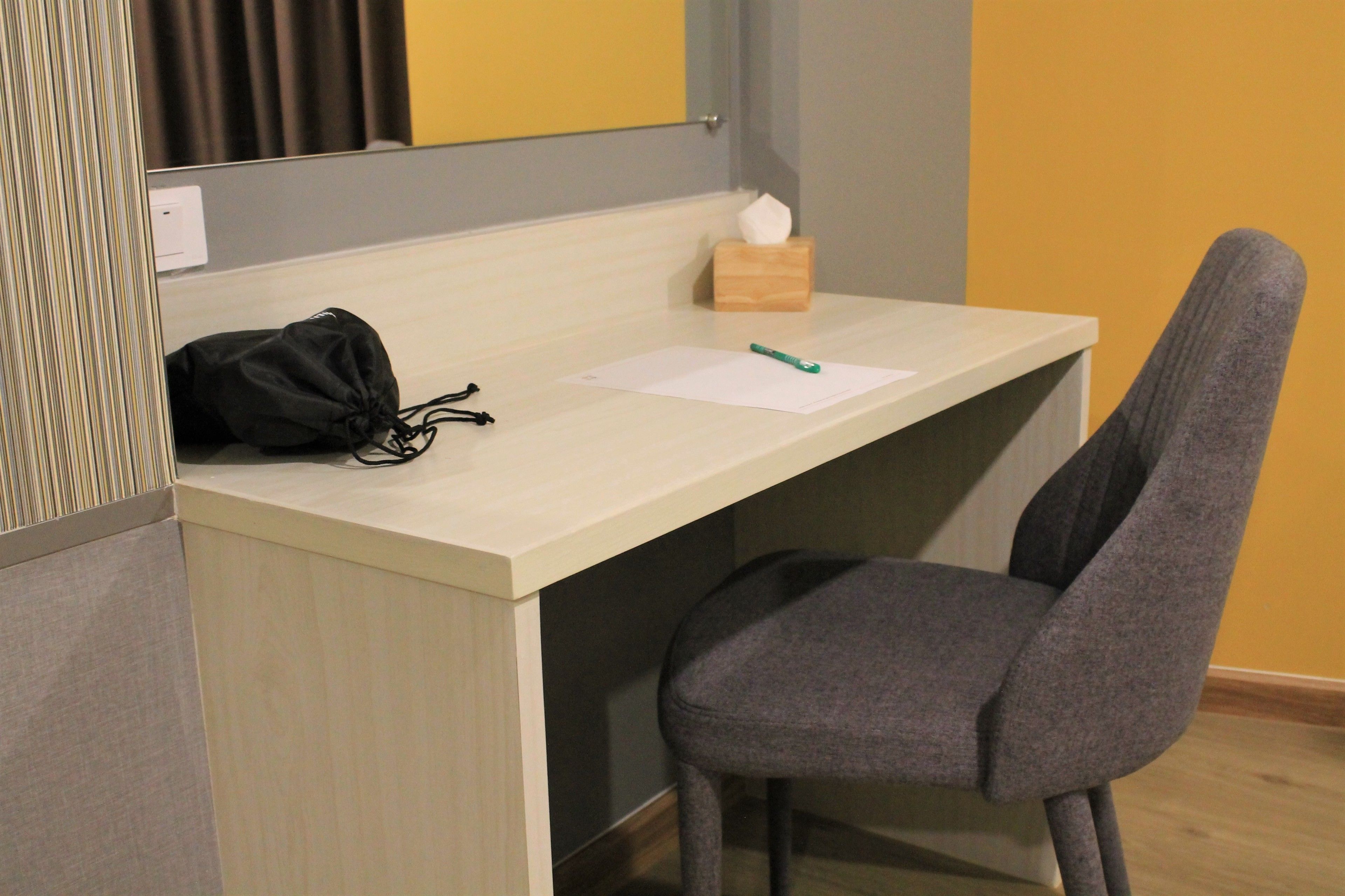 A small, neatly organized workspace with a desk, chair, and a tissue box.