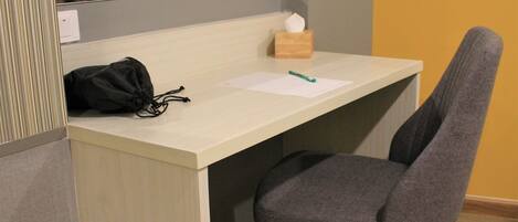 A small, neatly organized workspace with a desk, chair, and a tissue box.