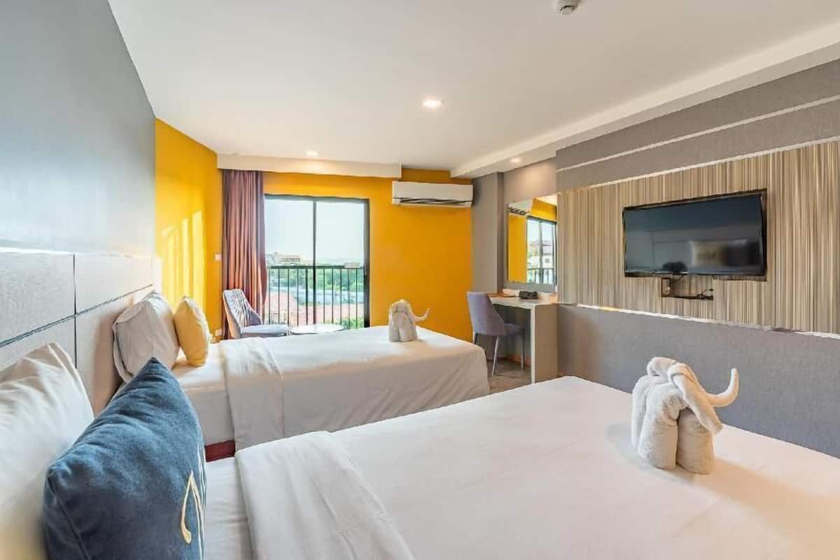 Ein Hotelzimmer mit zwei Betten, einem Schreibtisch, einem Fernseher und einem Balkon mit Blick.