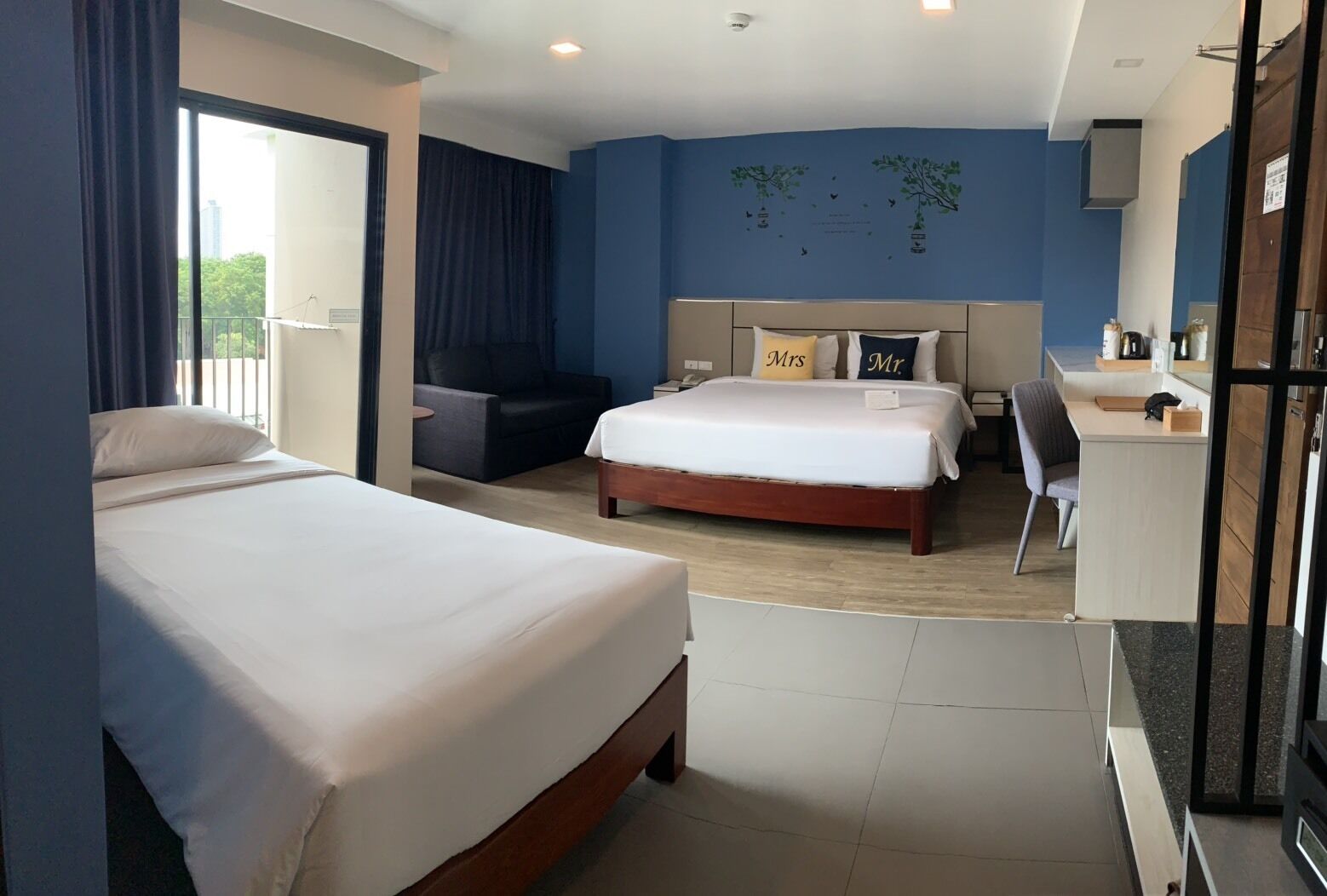 Ein Hotelzimmer mit zwei Betten, einem Schreibtisch, einem Stuhl und einem Balkon.