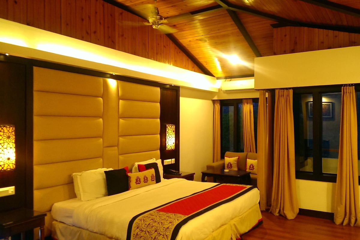 A bedroom with a bed, bedside tables, a window with curtains, and a wooden ceiling.