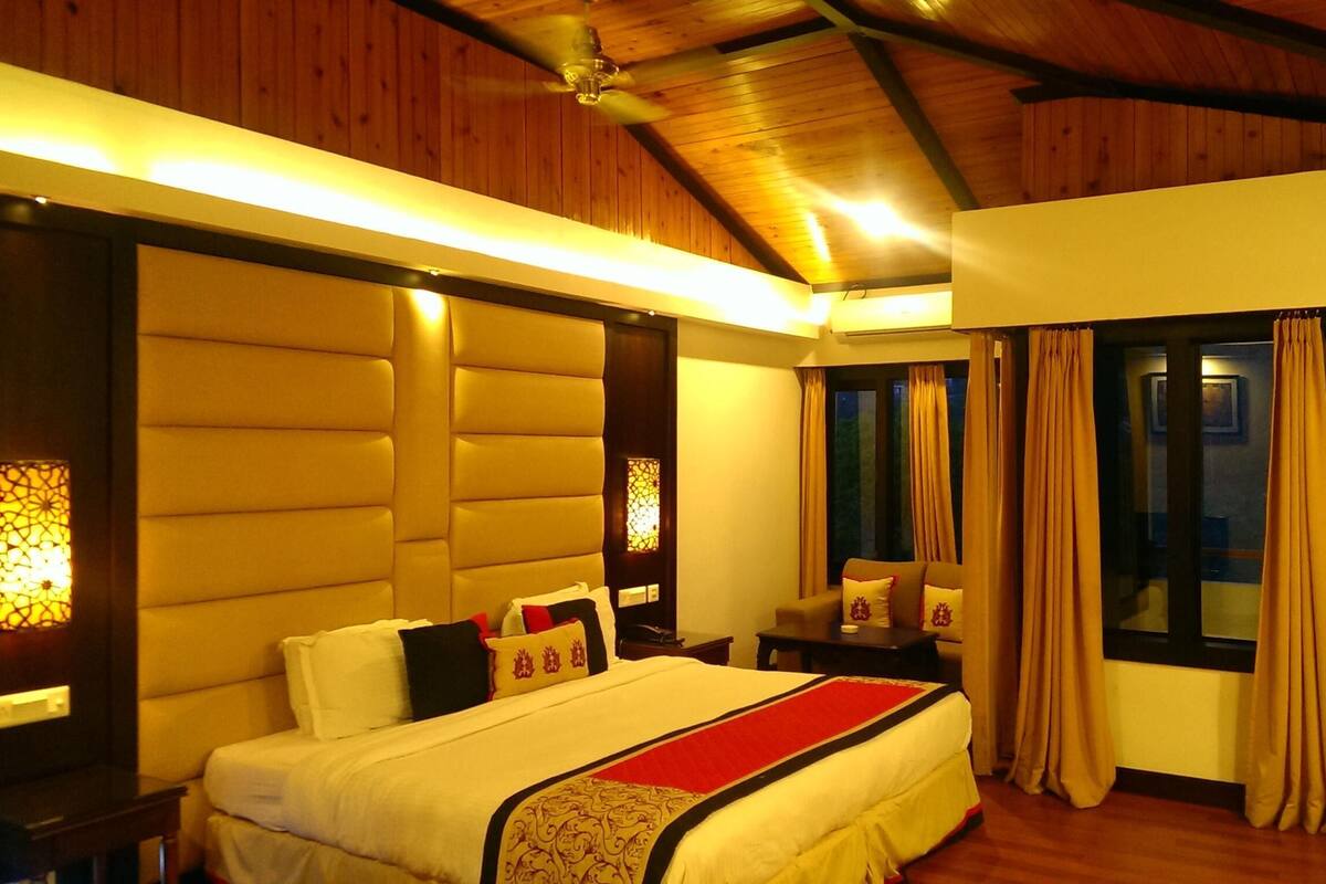 A bedroom with a bed, bedside tables, a window with curtains, and a wooden ceiling.