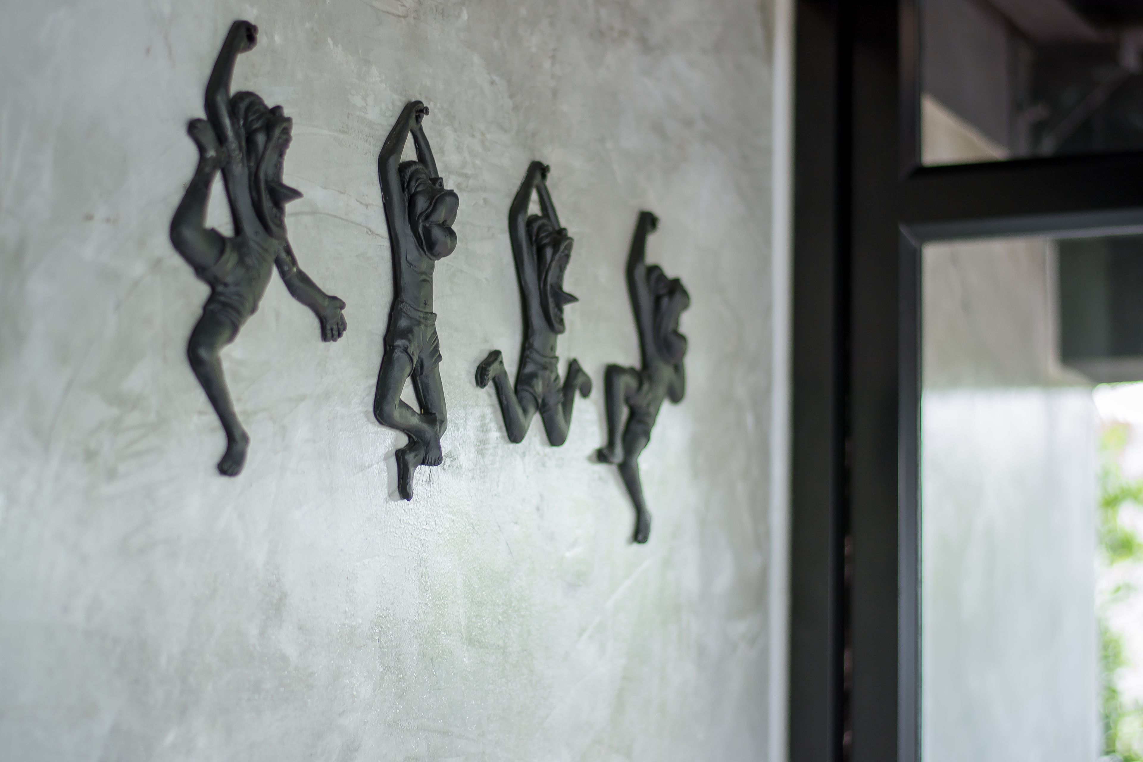 Un mur orné de plusieurs sculptures noires représentant des personnes dans différentes poses.