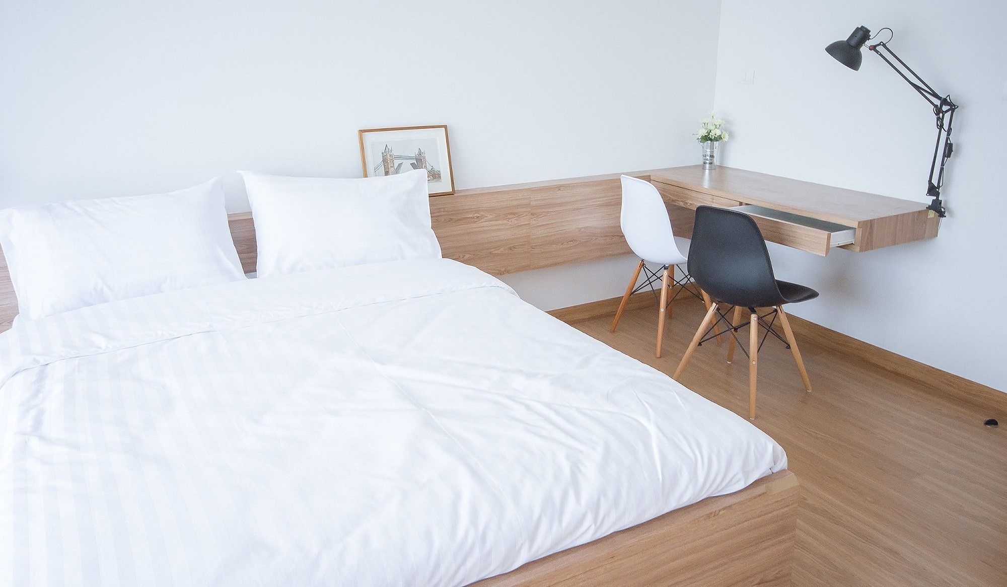 Une chambre à coucher avec un lit, un bureau avec une chaise, une lampe et un tableau au mur.