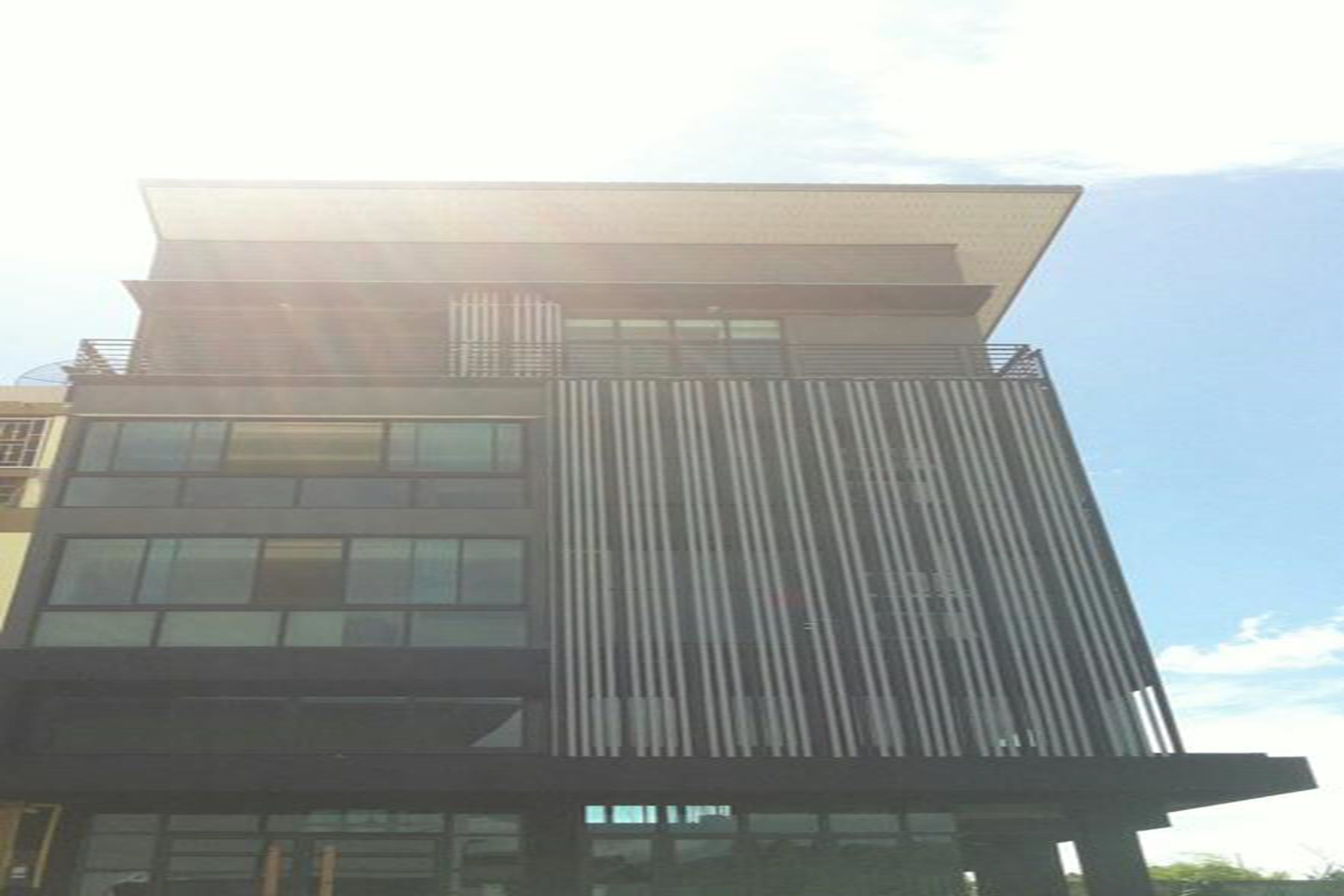 Un edificio moderno con techo plano, ventanas amplias y listones verticales en la fachada.