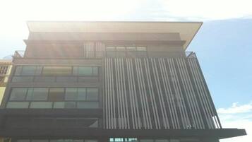 Un edificio moderno con techo plano, ventanas amplias y listones verticales en la fachada.